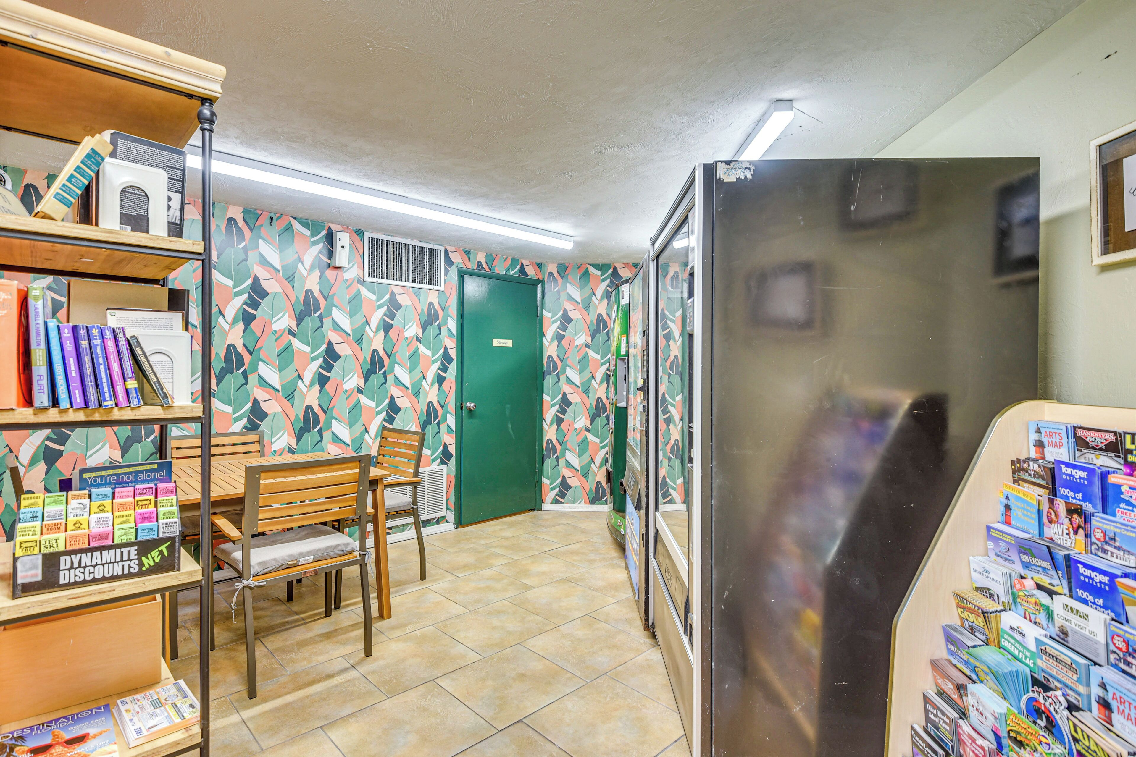 Un couloir avec une porte verte, un réfrigérateur rempli de magazines et un banc en bois.