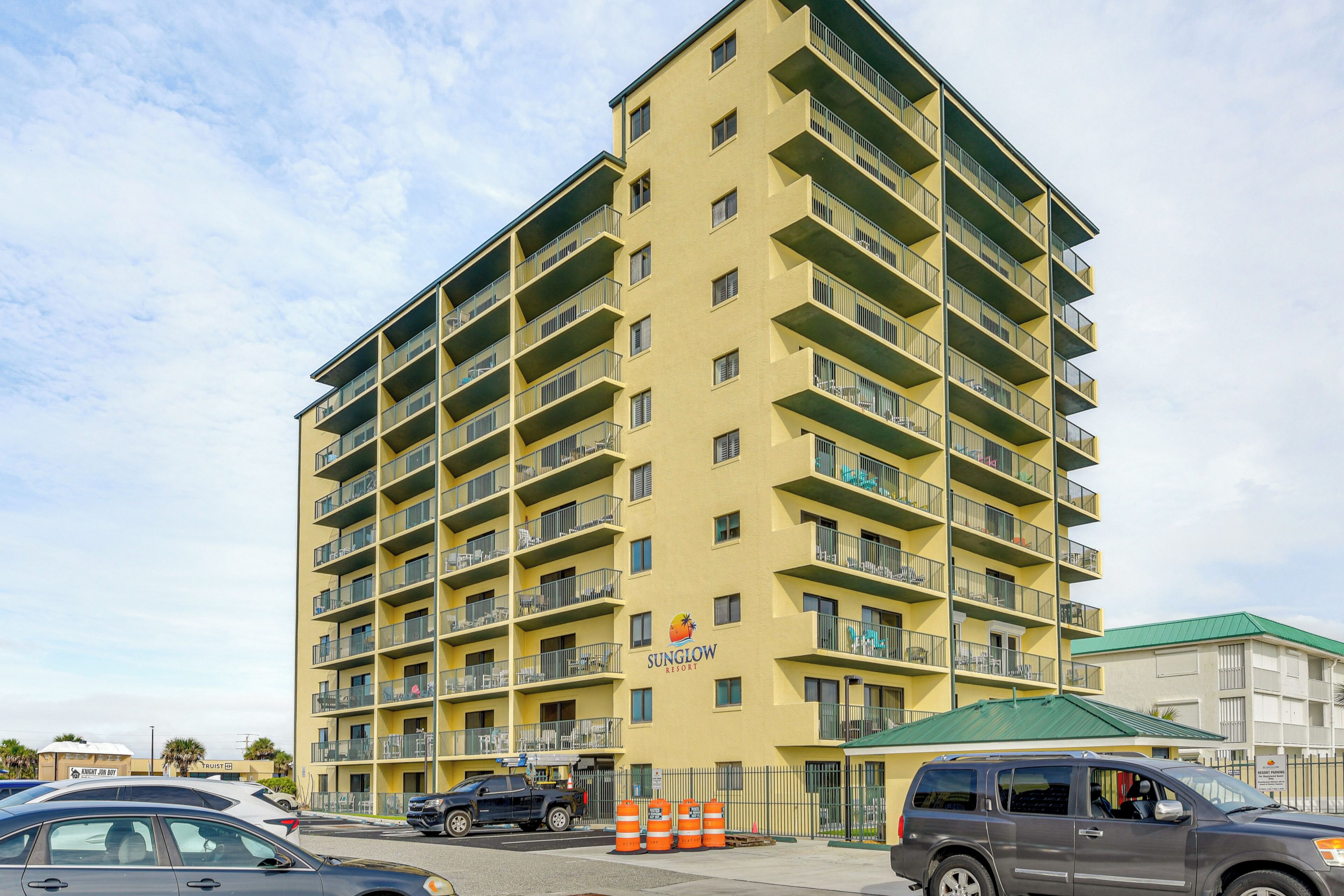 A multi-story hotel with balconies, a green roof, and a sign for 'Sunglow Resort'.
