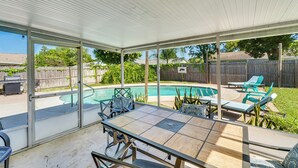 Um alpendre coberto com piscina, móveis de exterior e vista para o quintal.