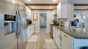 A modern kitchen with stainless steel appliances, white cabinetry, and a granite countertop. - Florida Vacation Rental w/ Screened Lanai (Ocala)