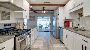 A kitchen with white cabinets, a stainless steel stove, and a ceiling fan. - Florida Vacation Rental w/ Screened Lanai (Ocala)