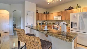 A modern kitchen with granite countertops, wooden cabinets, and stainless steel appliances. - ~ 9 Mi to Disney: Family Home w/ Private Pool! (Davenport)
