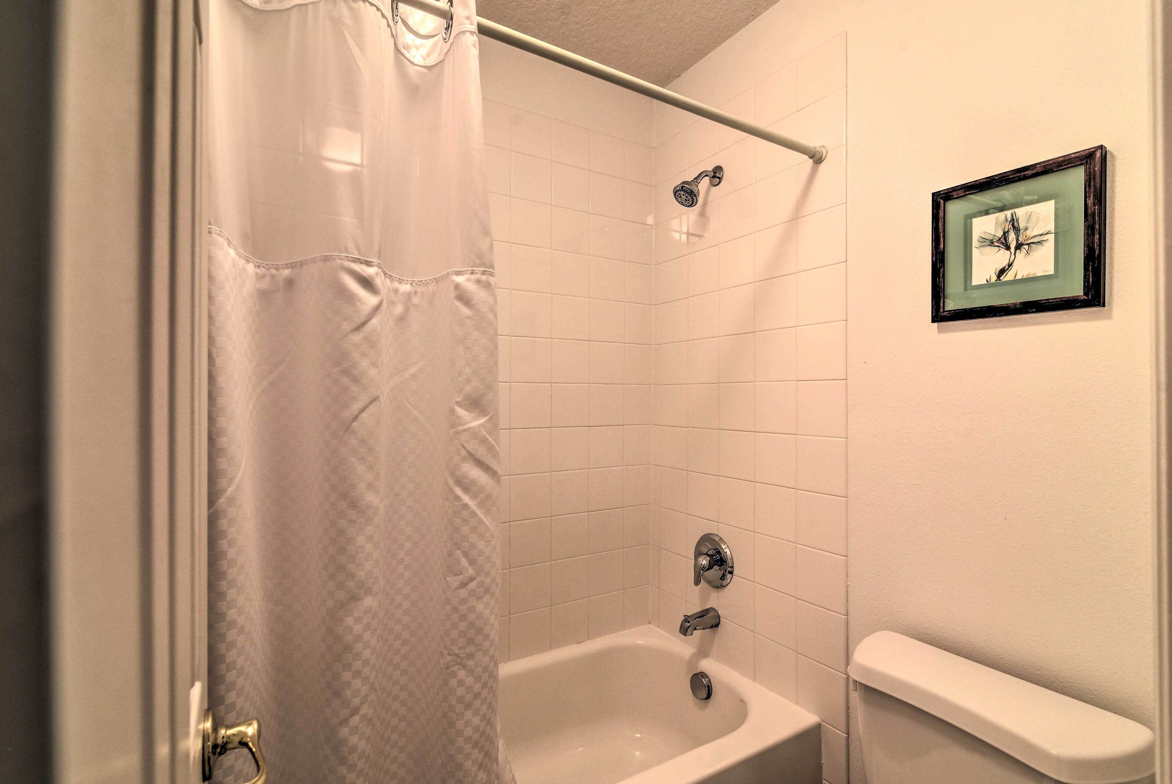 Un baño con bañera, cortina de ducha e imagen enmarcada en la pared.