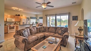 A spacious living room with a large sectional sofa, a glass coffee table, and a ceiling fan. - ~ 9 Mi to Disney: Family Home w/ Private Pool! (Davenport)
