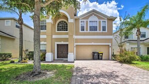 A two-story residential building with a beige facade, a central arched window, and a garage. - ~ 9 Mi to Disney: Family Home w/ Private Pool! (Davenport)