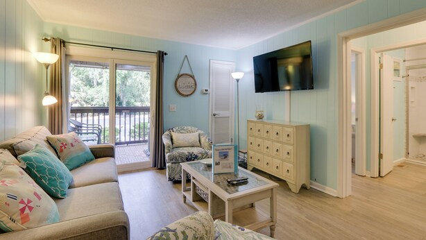 A living room with a sofa, armchairs, a coffee table, a TV, and a view of the outdoors. - Steps to Beach, Coligny Plaza: Hilton Head Condo! (Hilton Head Island)