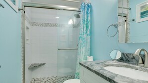A bathroom with a glass-enclosed shower, a white toilet, a marble sink, and a mirror. - Steps to Beach, Coligny Plaza: Hilton Head Condo! (Hilton Head Island)