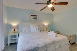A bedroom with a bed, a ceiling fan, a nightstand, and a bedside table.