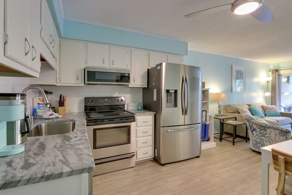 A modern kitchen with white cabinets, stainless steel appliances, and a marble countertop.