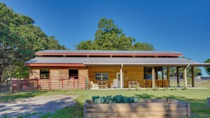 Un bâtiment en bois doté d’un porche couvert, d’un espace clôturé et d’un parterre.