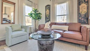 Ein Wohnzimmer mit einem braunen Ledersofa, einem hellgrauen Sessel und einem Couchtisch mit Glasplatte.