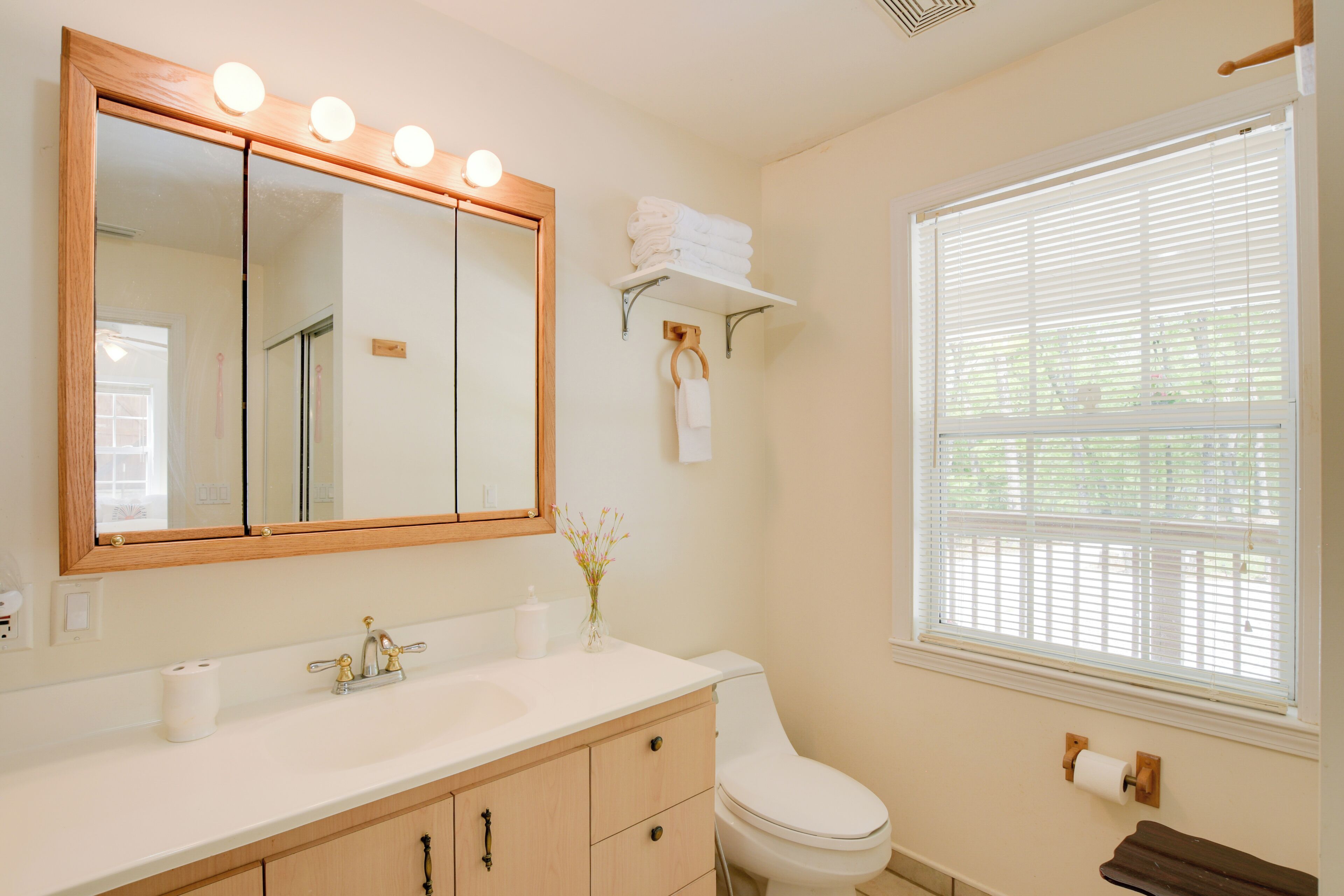 A bathroom with a vanity, sink, mirror, and toilet.