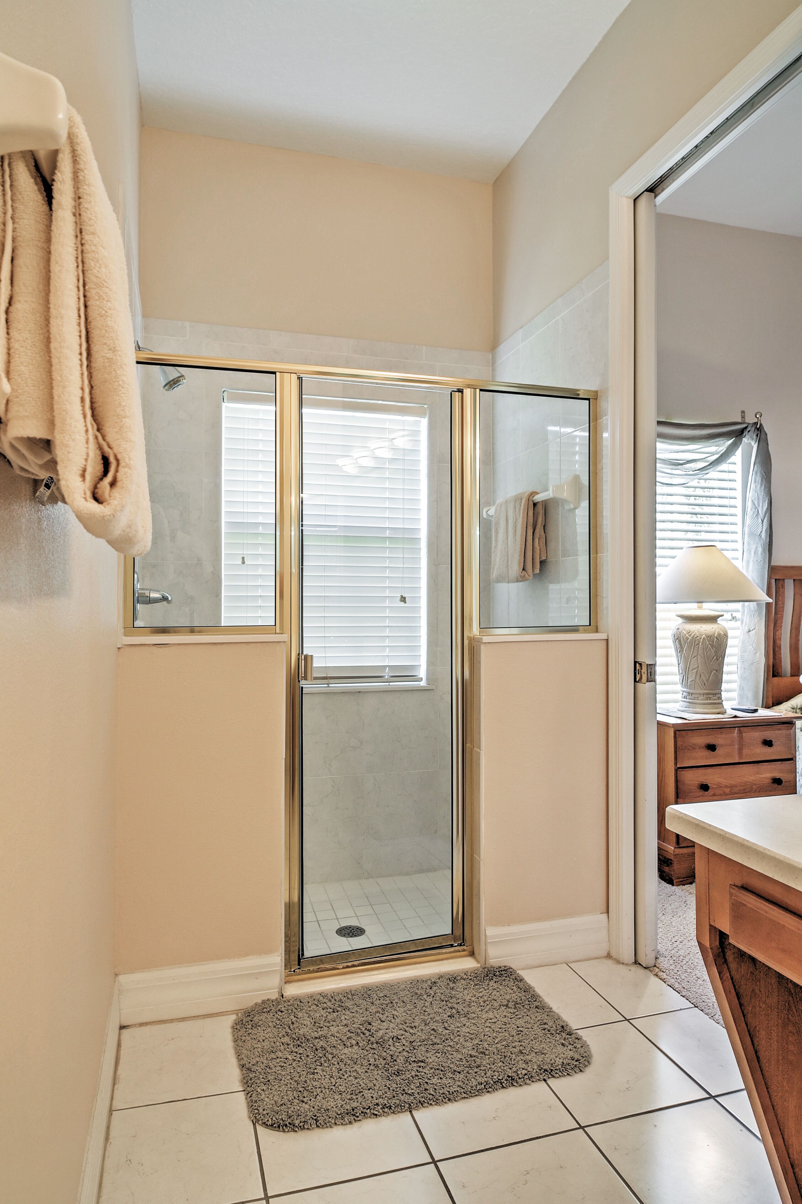 A bathroom with a glass shower enclosure, a towel rack, a sink, and a vanity with a mirror.
