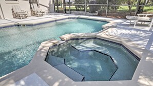 Une piscine avec un jacuzzi, des chaises longues et un espace patio.