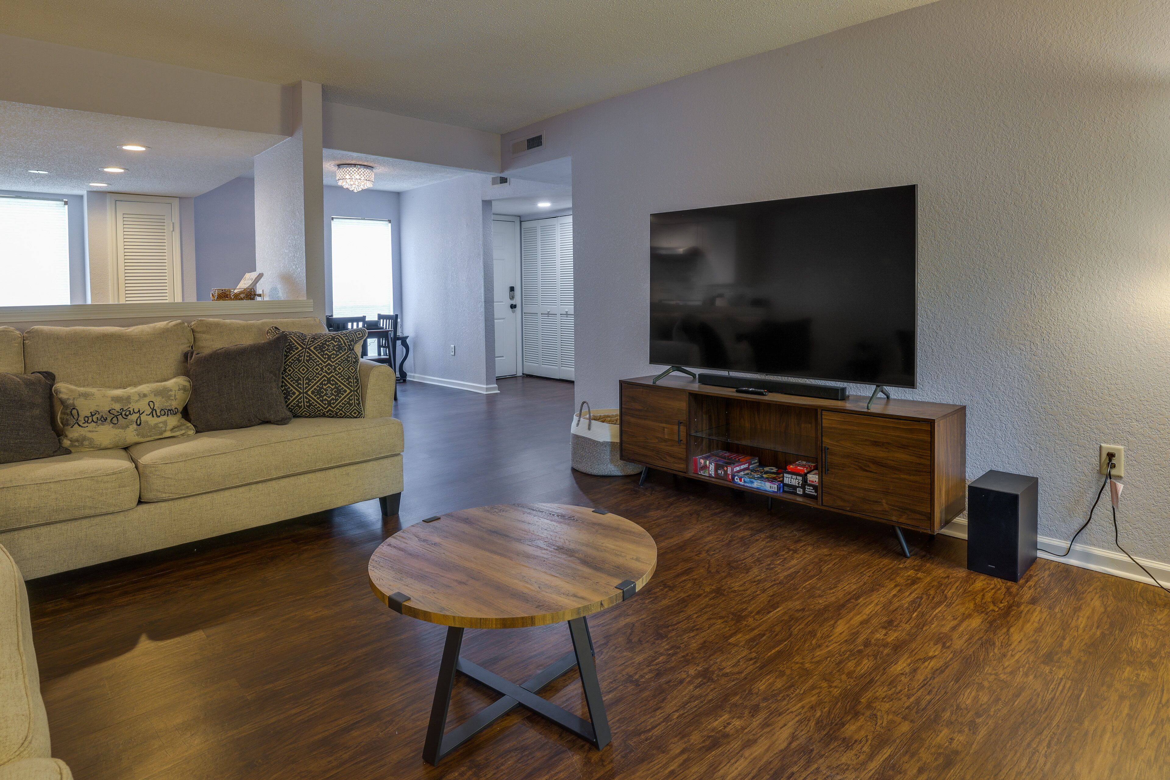 A living room with a sofa, a coffee table, a TV on a wooden stand, and a speaker.