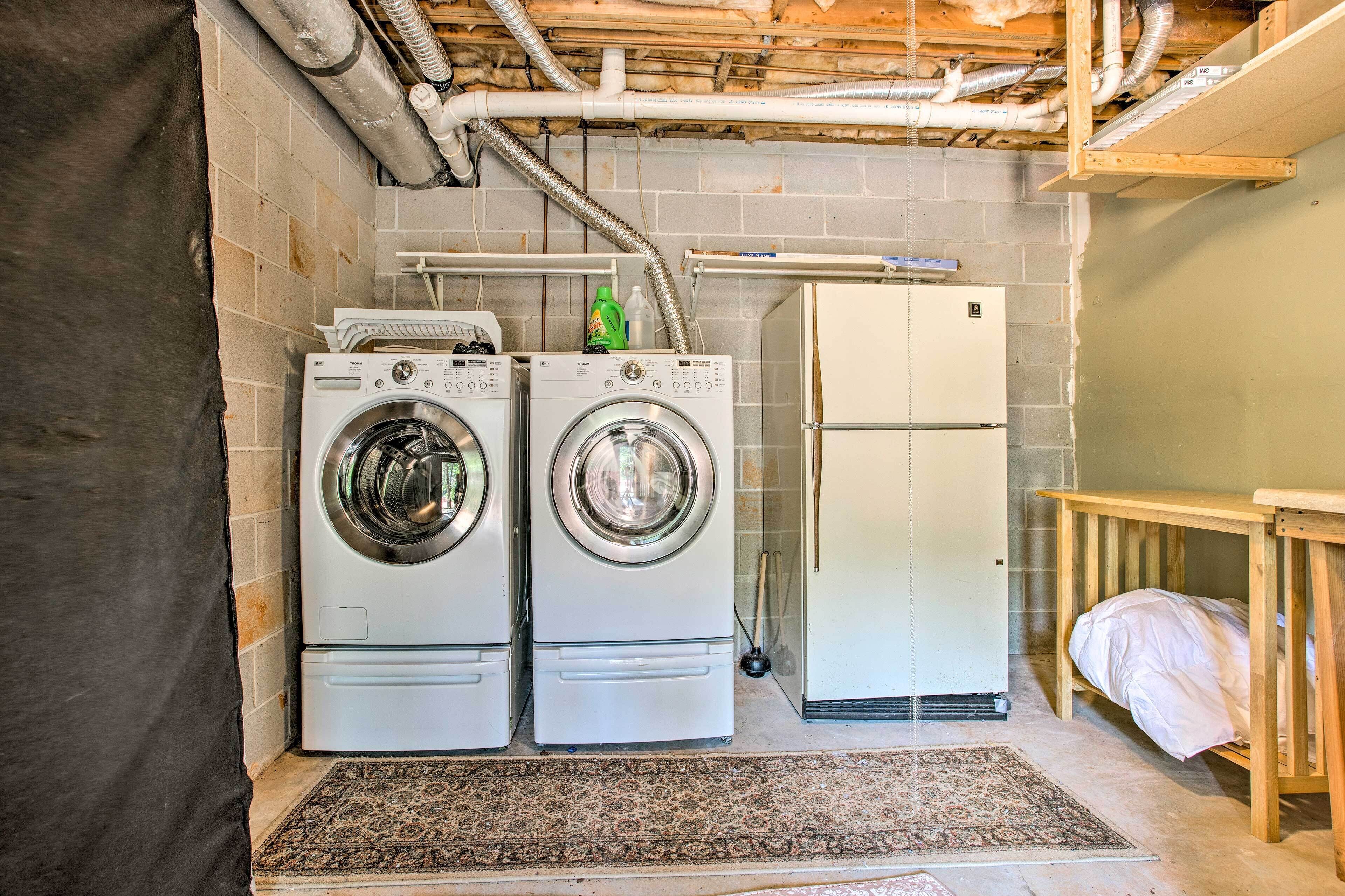 Un cuarto de lavado con dos lavadoras de carga frontal, un refrigerador y un banco de madera.