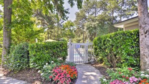 A gated entrance to a property surrounded by lush greenery and flower beds. - Walk to Beach: Resort-style Hilton Head Condo! (Hilton Head Island)