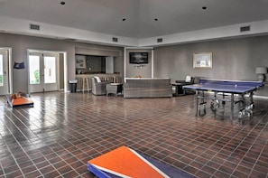 A spacious living area with a ping pong table, seating, and a television.