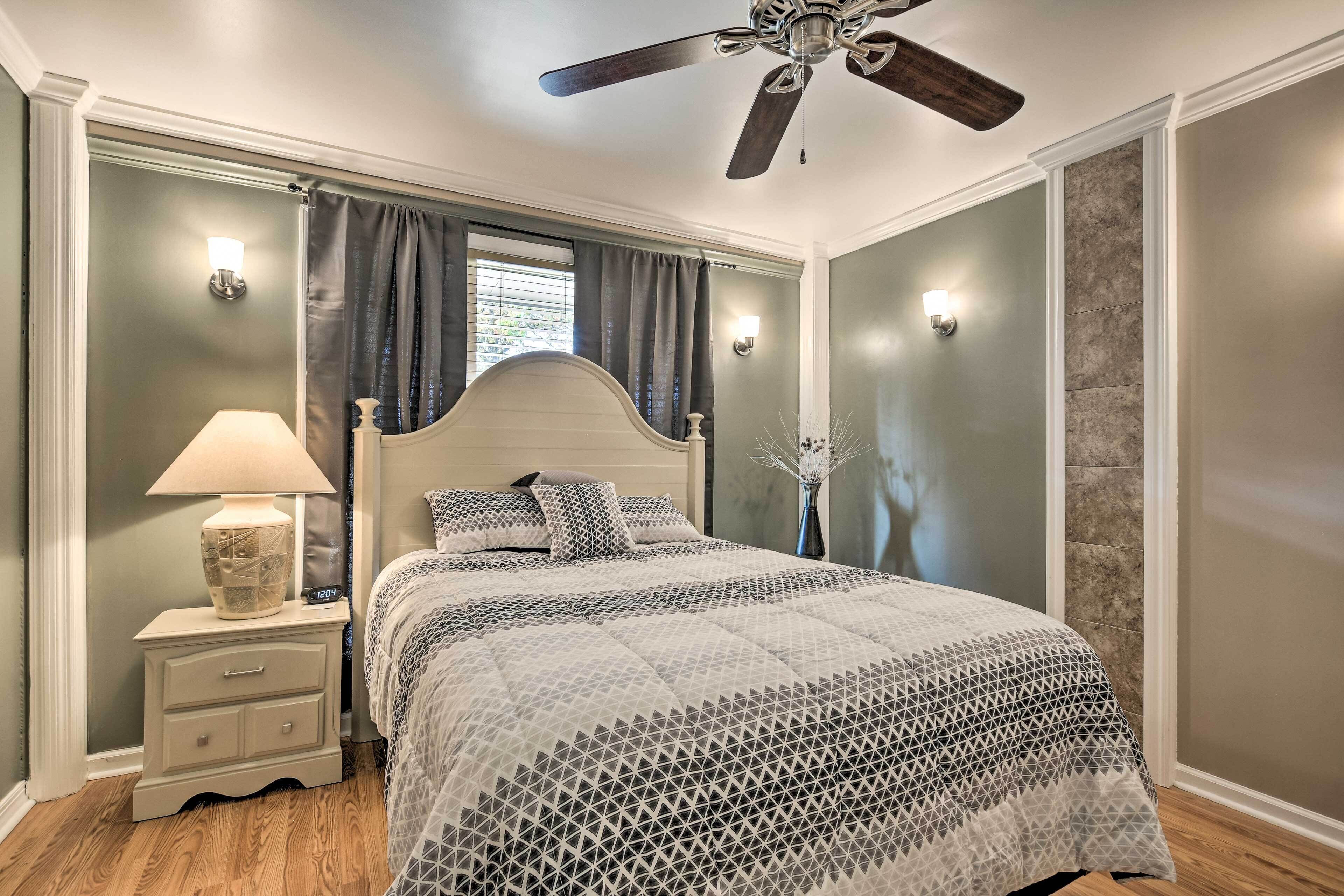 A bedroom with a bed, nightstand, lamp, and ceiling fan.