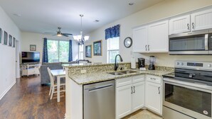 A modern kitchen with white cabinets, stainless steel appliances, and a granite countertop.
