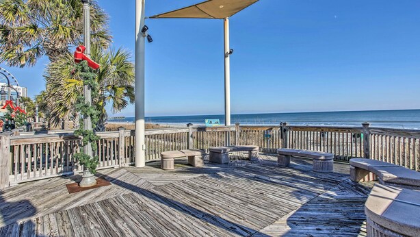 A wooden deck with benches and a view of the ocean.