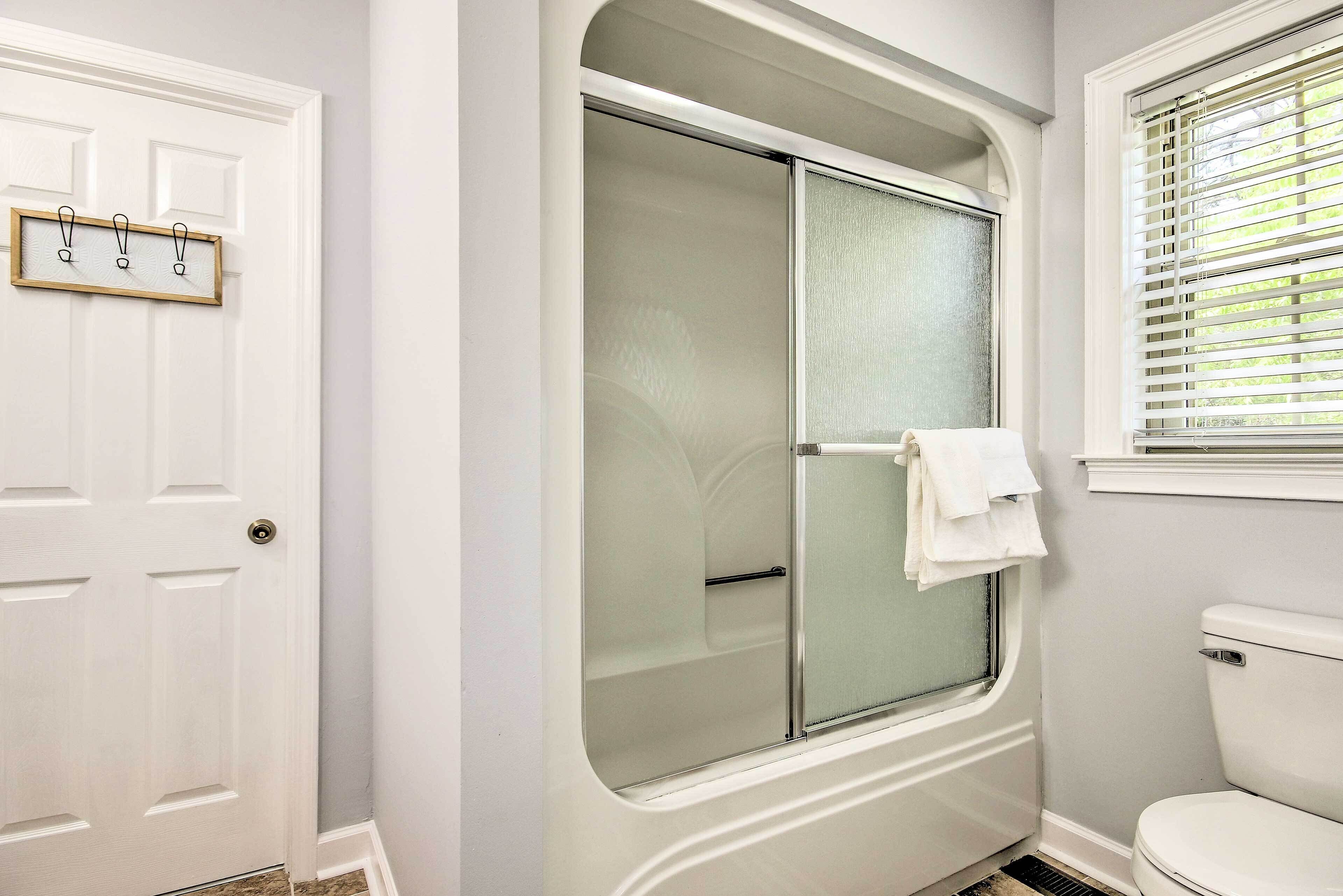 A bathroom with a shower, toilet, and a door with a towel rack.