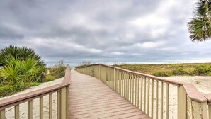 A wooden boardwalk with railings, leading to a beach area with sand and sparse vegetation. - Hilton Head Escape w/ Private Beach Access! (Hilton Head Island)