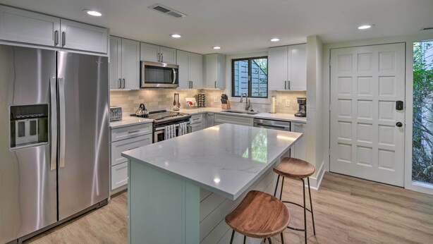 A modern kitchen with stainless steel appliances, a large island, and wooden bar stools. - Hilton Head Escape w/ Private Beach Access! (Hilton Head Island)