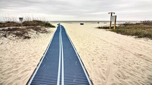 A beach path with a blue running track, a signpost, and a beach area.