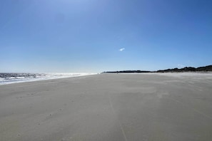 Uma praia larga e deserta, com céu limpo.