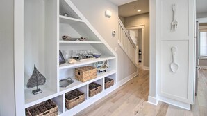 Un interior moderno con una escalera, estanterías blancas con cestas y una puerta decorada con una cuchara.