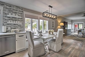 A modern kitchen with white cabinetry, a stone backsplash, and a dining area with white chairs and a table. - Pet-friendly Villa w/ Balcony in Bluffton! (Bluffton)
