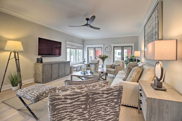 A modern living room with a sofa, ottoman, coffee table, and a TV mounted on the wall. - Pet-friendly Villa w/ Balcony in Bluffton! (Bluffton)