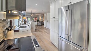 Una cocina moderna con electrodomésticos de acero inoxidable, una isla central y un comedor con candelabro.