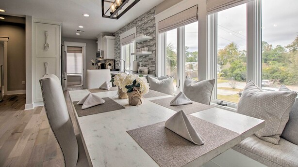 Un comedor moderno con una mesa de mármol, sillas acolchadas y vistas al exterior.