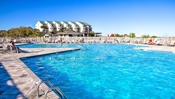 A swimming pool with clear blue water, a lifeguard chair, and a poolside area with lounge chairs. - Beach View, Pool & Tennis: Hilton Head Island Unit (Hilton Head Island)