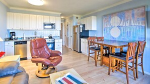 A modern kitchen with white cabinets, stainless steel appliances, and a dining area with wooden chairs and a table. - Beach View, Pool & Tennis: Hilton Head Island Unit (Hilton Head Island)