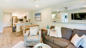Un salon moderne comprenant un canapé, un fauteuil et un coin repas avec une table et des chaises.