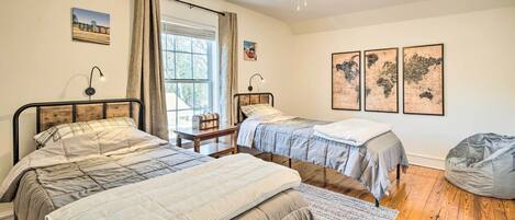 Un dormitorio con dos camas, ventilador de techo, ventana con cortinas y decoración en la pared.