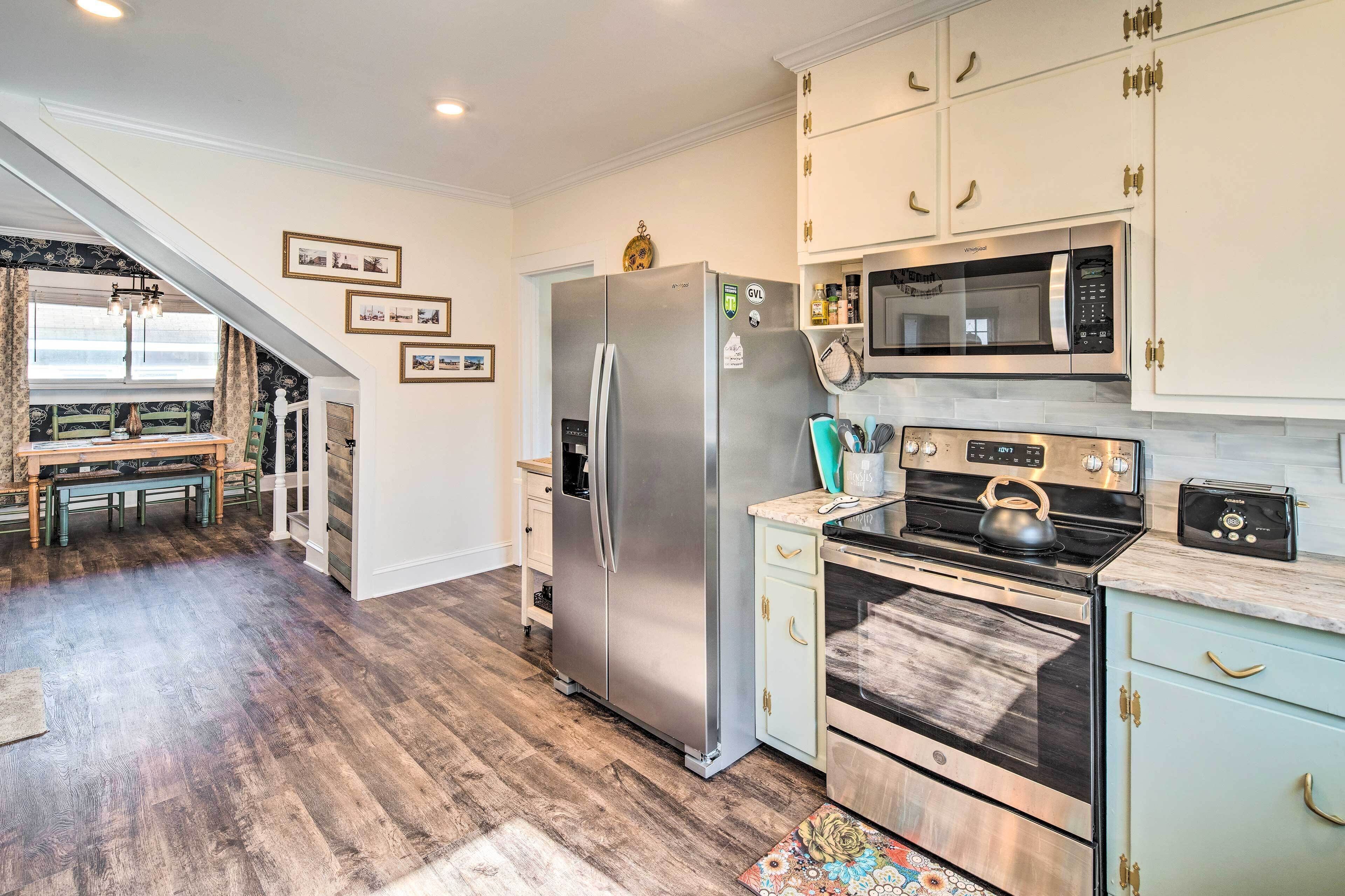 A modern kitchen with stainless steel appliances, a microwave, and a kettle on the stove.