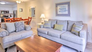 A living room with two grey sofas, a wooden coffee table, and a dining area with a table and chairs. - Hilton Head Condo: Pool, Hot Tub & Tennis Access! (Hilton Head Island)