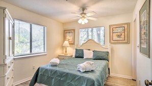 A bedroom with a bed, two bedside tables, a nightstand, a ceiling fan, and two windows with blinds. - Hilton Head Condo: Pool, Hot Tub & Tennis Access! (Hilton Head Island)