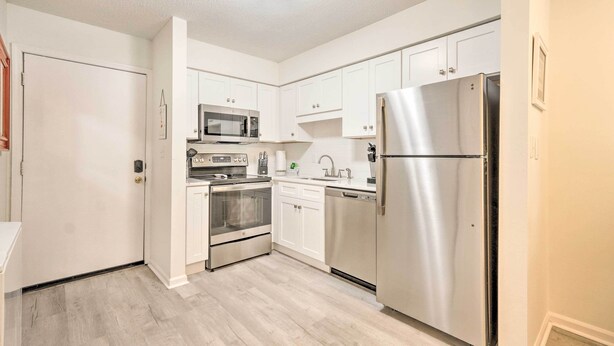 A modern kitchen with stainless steel appliances, white cabinetry, and a wooden floor. - Hilton Head Condo: Pool, Hot Tub & Tennis Access! (Hilton Head Island)