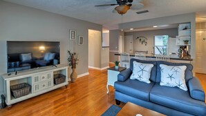 A living room with a flat-screen TV, a blue sofa, and a ceiling fan. - Breezy Sarasota Home w/ Private Pool Near Beach! (Sarasota)