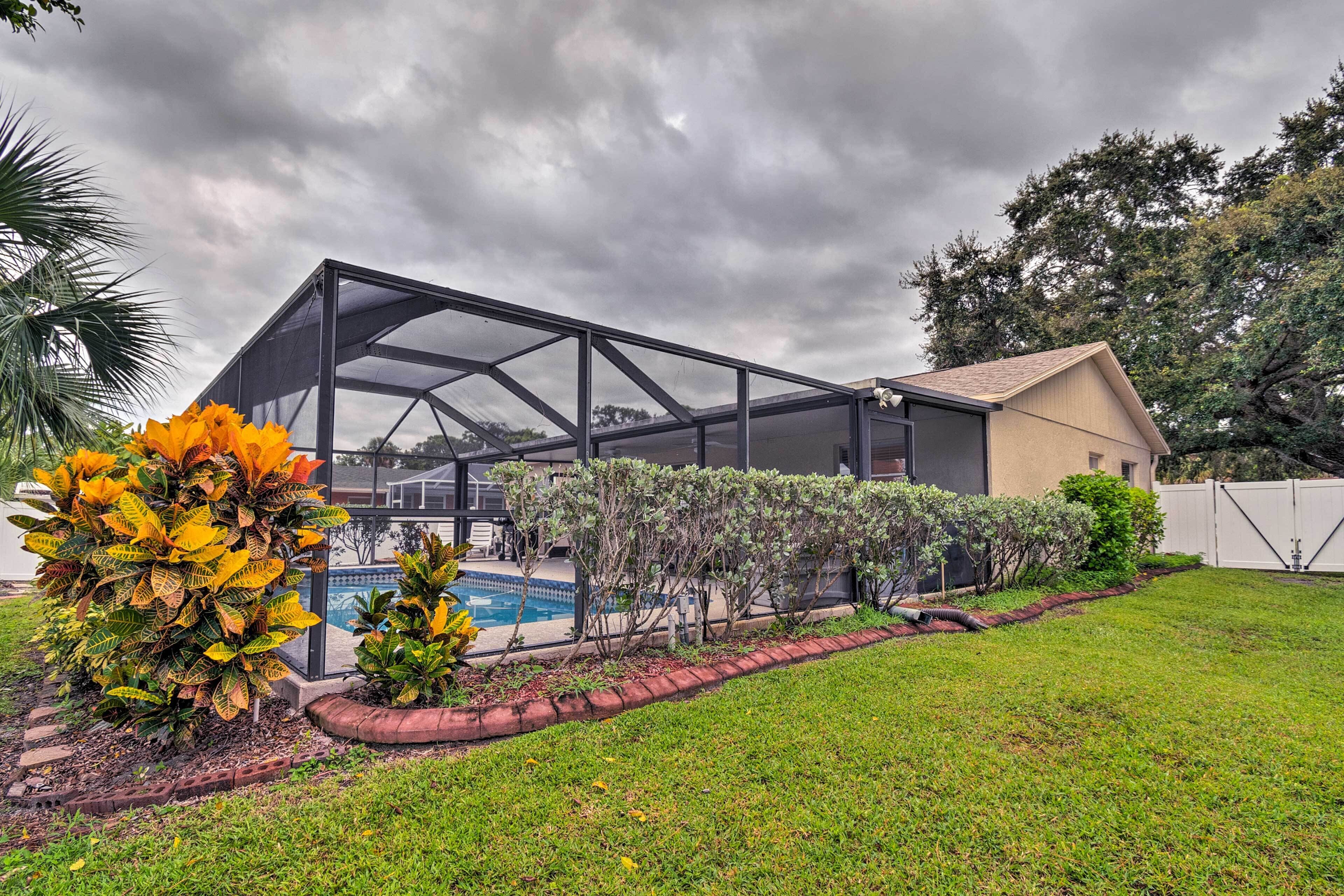 A house with a covered patio, a swimming pool, and a well-maintained lawn.