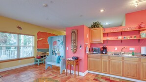 A kitchen with wooden cabinets, a sink, and a countertop. There is a window with blinds, a small table, and a bench. - Vibrant Condo - Walk to Indian Rocks Beach! (Indian Rocks Beach)