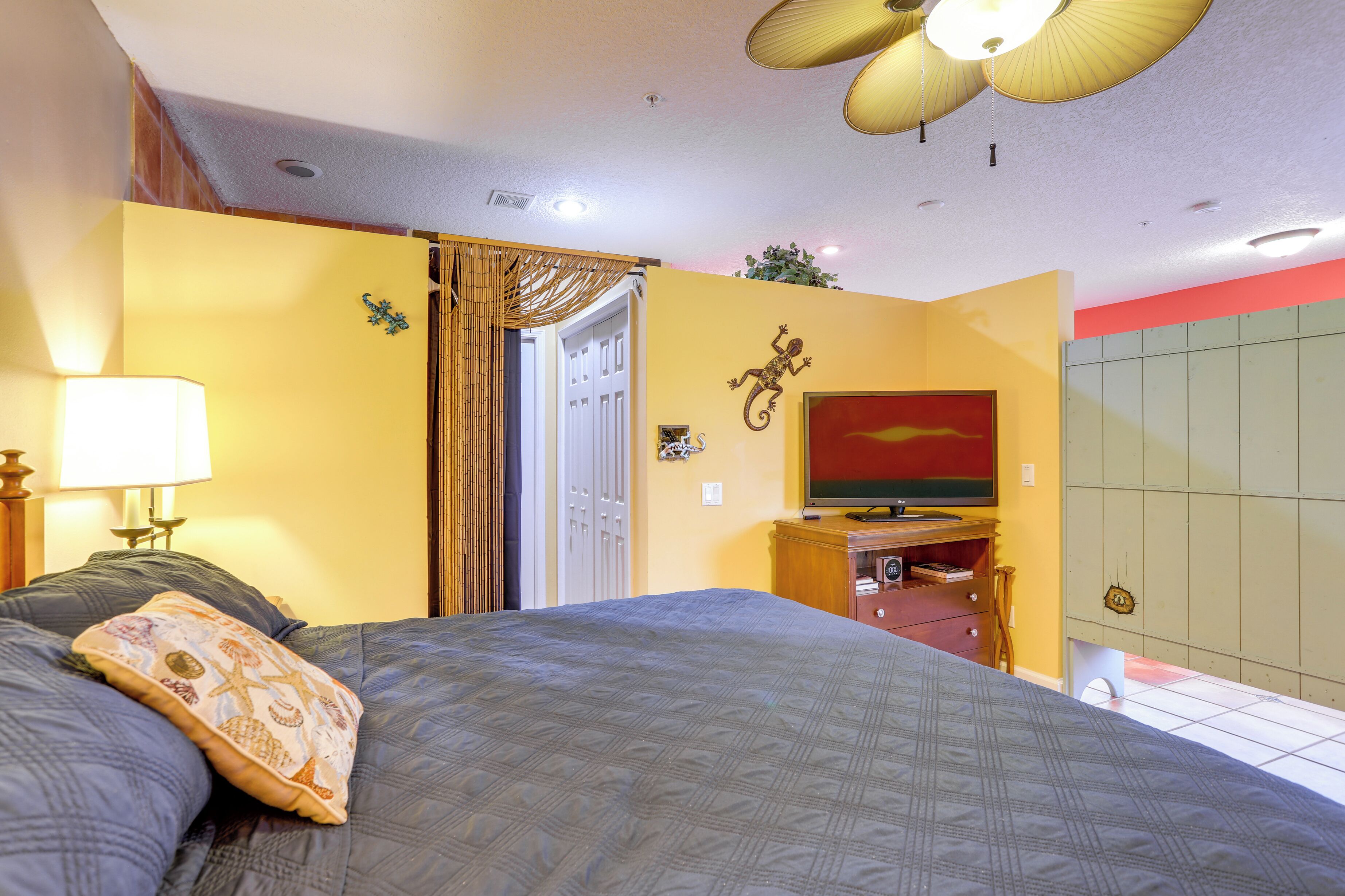 A bedroom with a bed, a television, a wardrobe, and a door leading to another room.