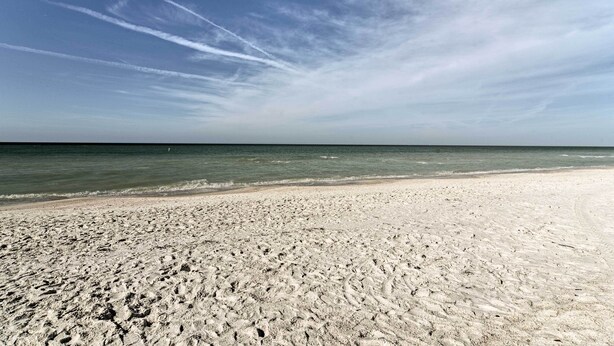 Een zandstrand met heldere lucht en zee.