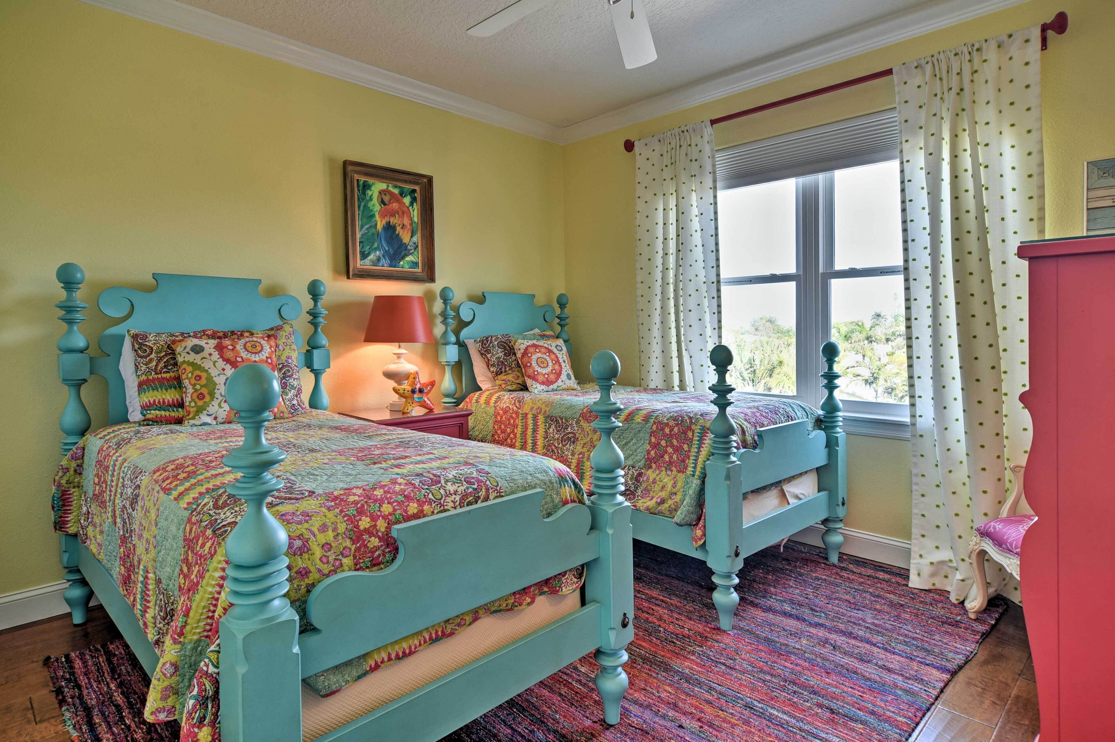 A bedroom with two twin beds, a window with curtains, and a nightstand with a lamp.