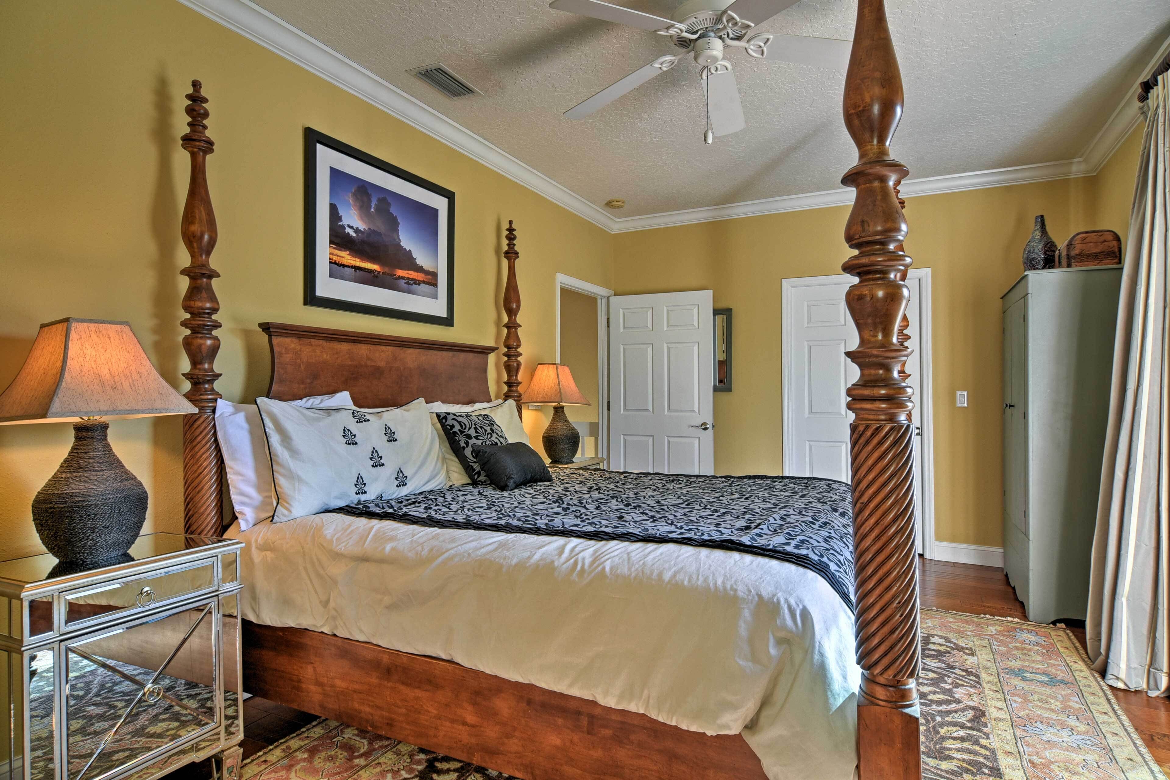 A four-poster bed with a wooden headboard, two bedside lamps, and a framed picture on the wall.